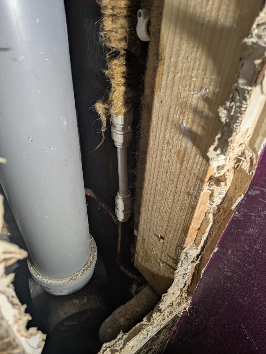 Temporary repair to the concealed mains-water pipe behind a tiled WC enclosure
